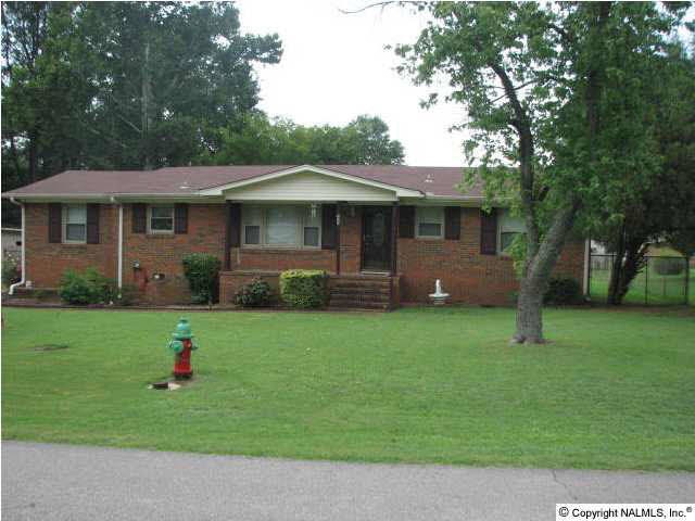 Front view of full brick home with mature trees and shrubs