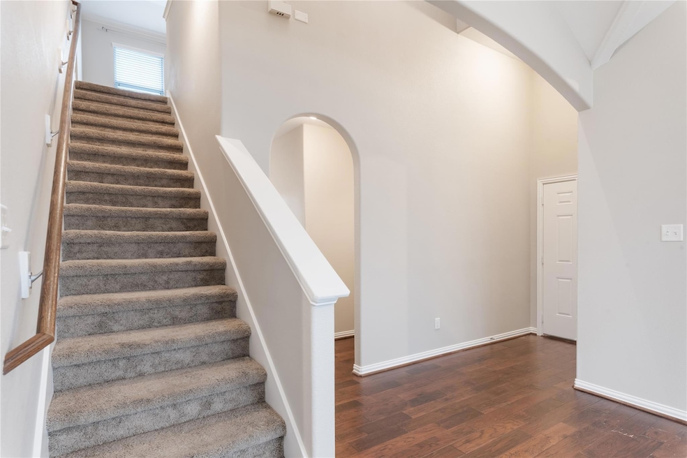 Staircase with wood finished floors and arched wa