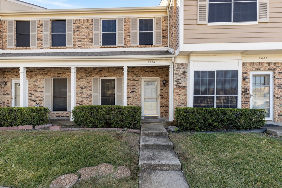 View of exterior entry with a yard, brick siding, and covered porch