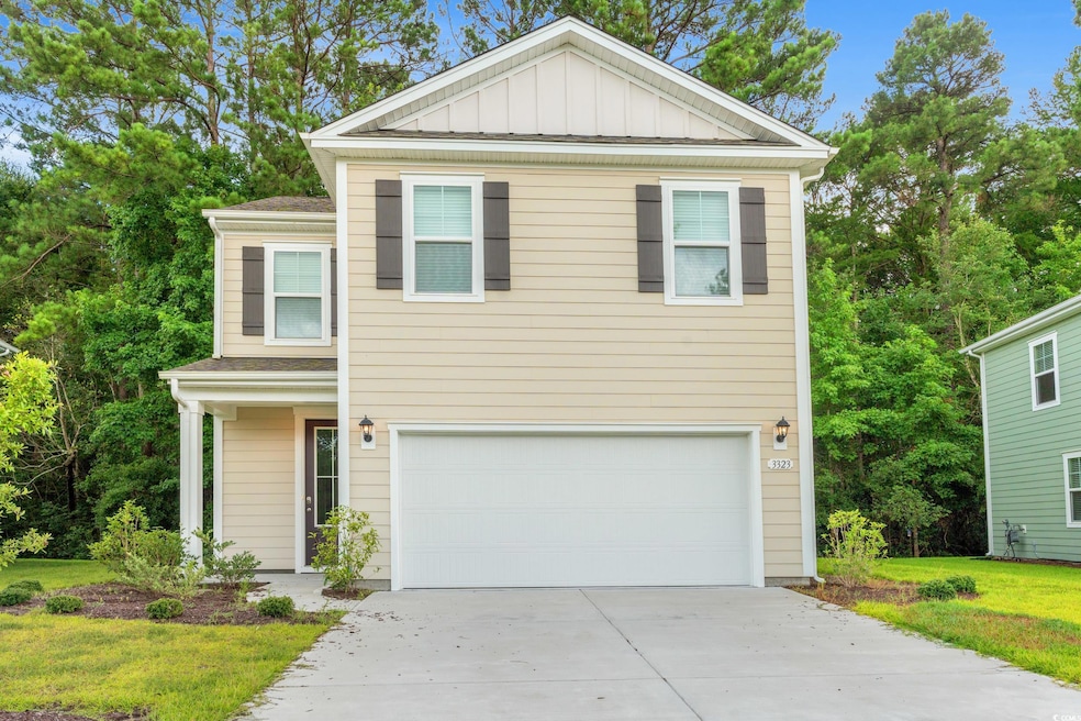 View of front of house featuring an attached garage, driveway, board and batten siding, and a front lawn