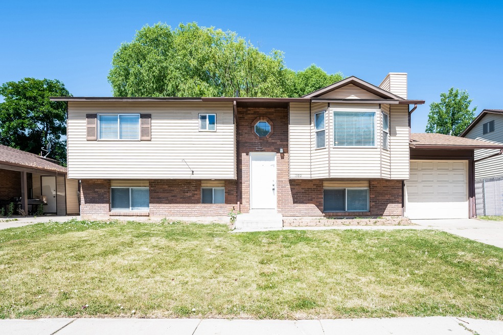 Raised ranch with brick siding, a front lawn, and a chimney