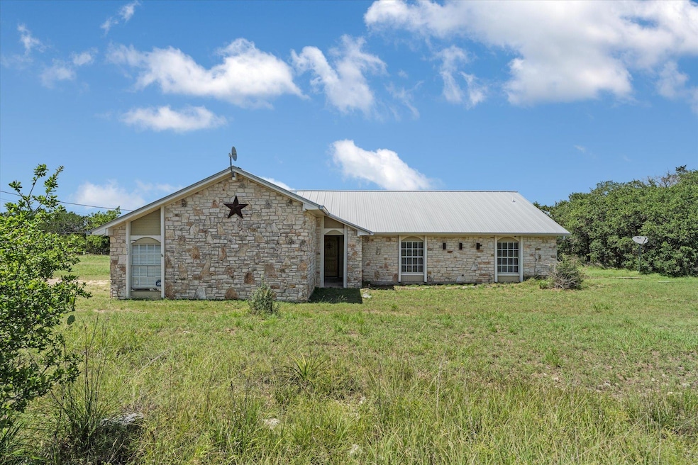 Back of property featuring stone siding, a metal 