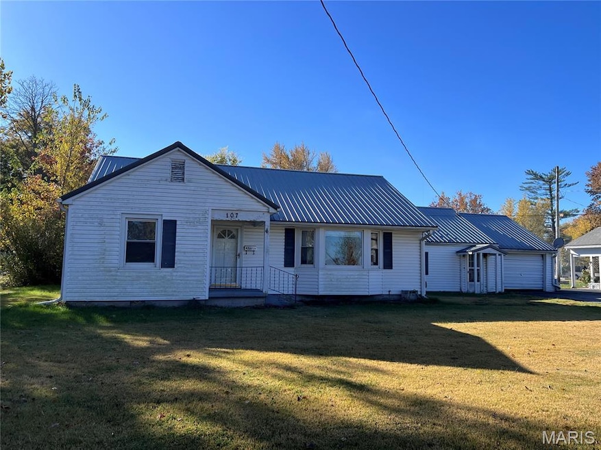 View of front facade featuring a front yard, a metal roof, and a garage