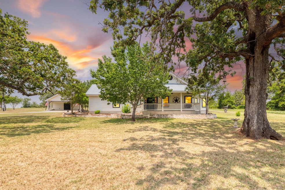 Yard at dusk with covered porch, a lawn, and a ca