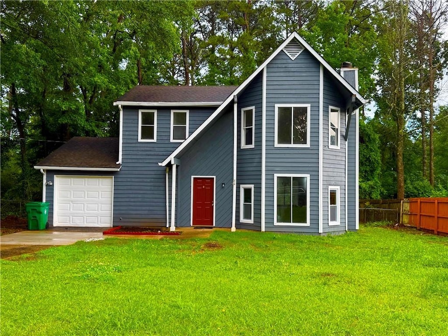 View of front of house featuring a chimney, concrete driveway, an attached garage, and a shingled roof