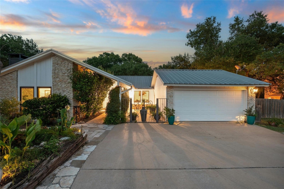 View of front of property featuring stone siding, driveway, a metal roof, and board and batten siding