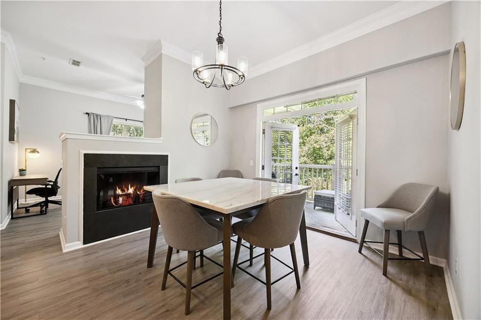 Dining room featuring ornamental molding, wood finished floors, a warm lit fireplace, and a chandelier