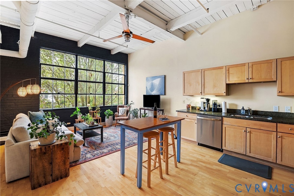 Living area with kitchen featuring stainless steel dishwasher, light wood-style floors, ceiling fan, dark stone countertops, and a wood ceiling with exposed beams