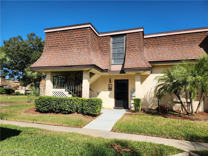 View of front of property with a shingled roof, a front lawn, stucco siding, and mansard roof