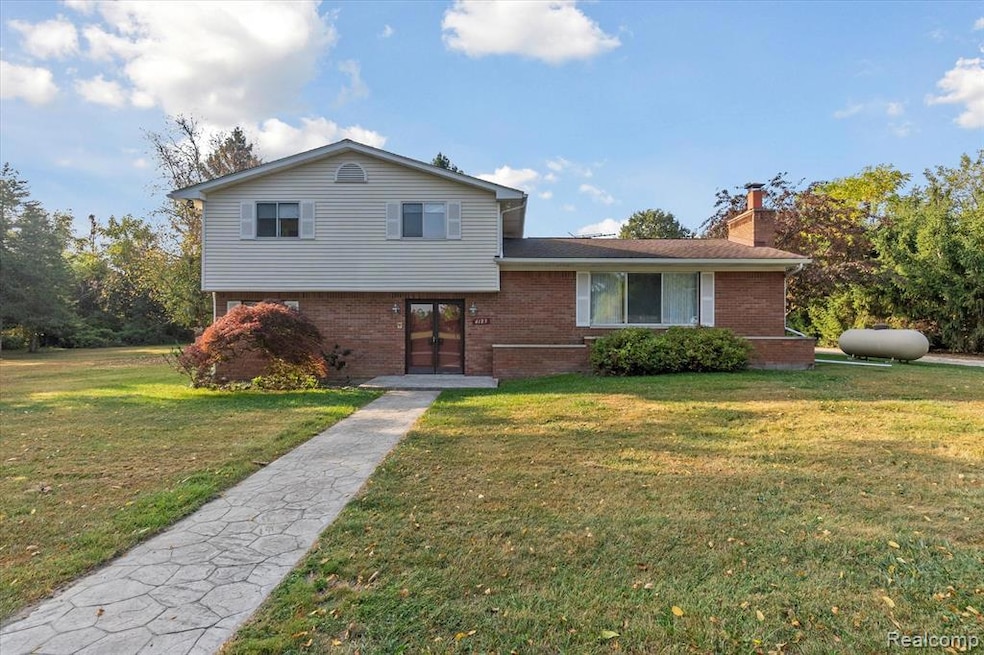 Tri-level home featuring brick siding, a front yard, and a chimney