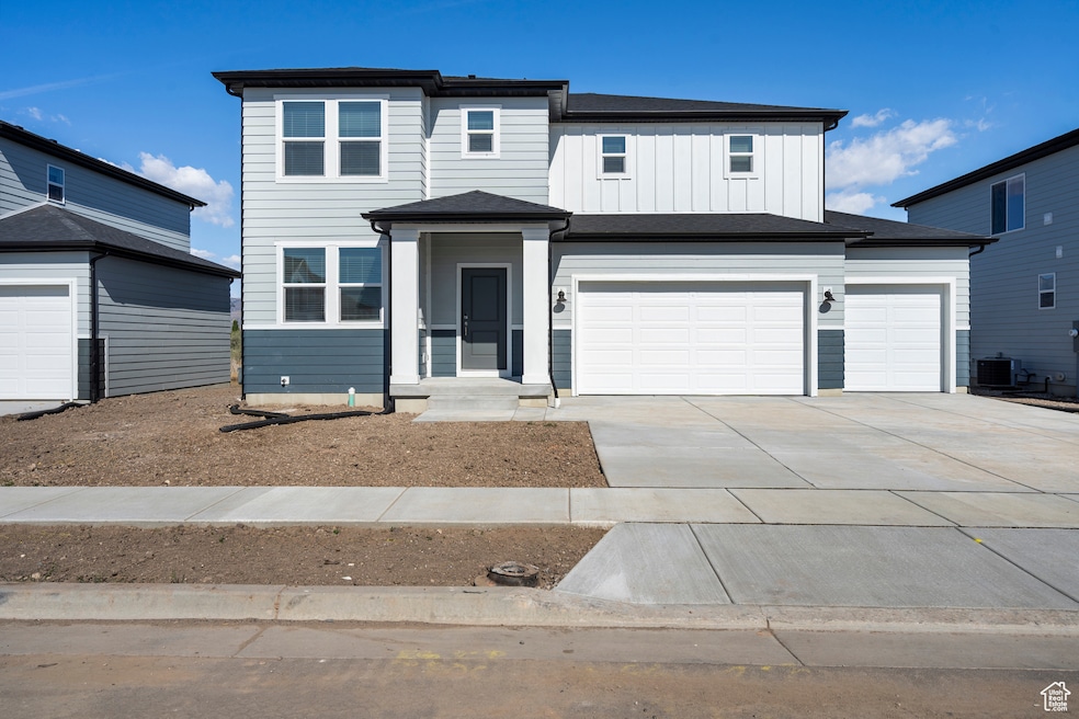View of front of home featuring concrete driveway, cooling unit, board and batten siding, and a garage