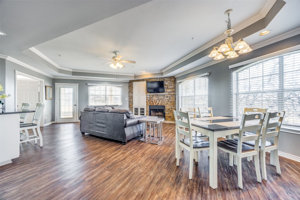 Dining area with dark wood-type flooring, a fireplace, plenty of natural light, and a tray ceiling