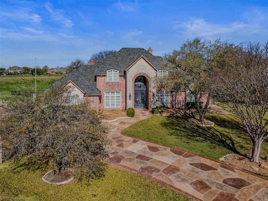 French country home with brick siding, a chimney, 