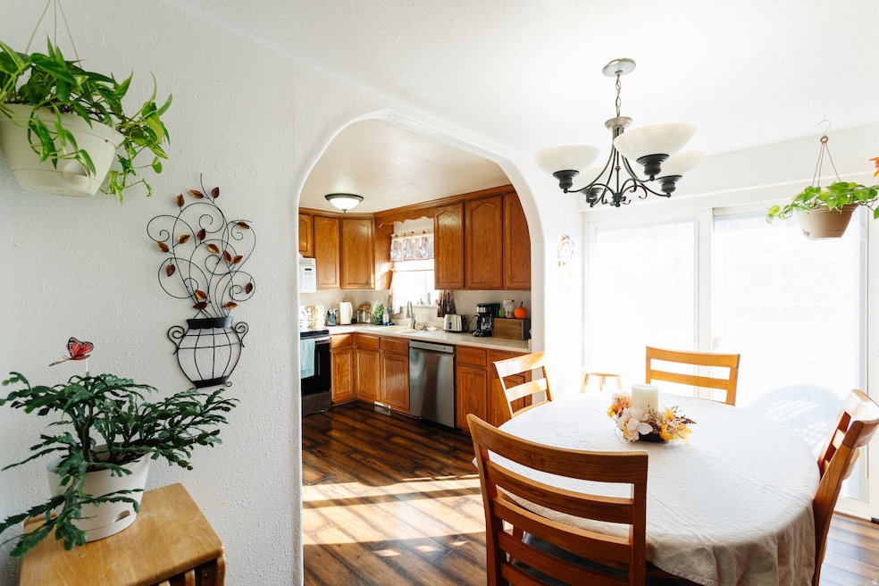 Dining area featuring dark wood-style flooring, arched walkways, a textured wall, and a chandelier