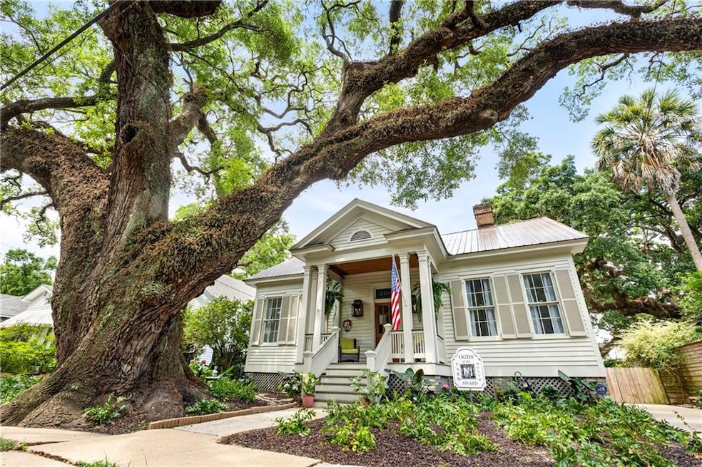 View of front of home with a chimney, a porch, and metal roof