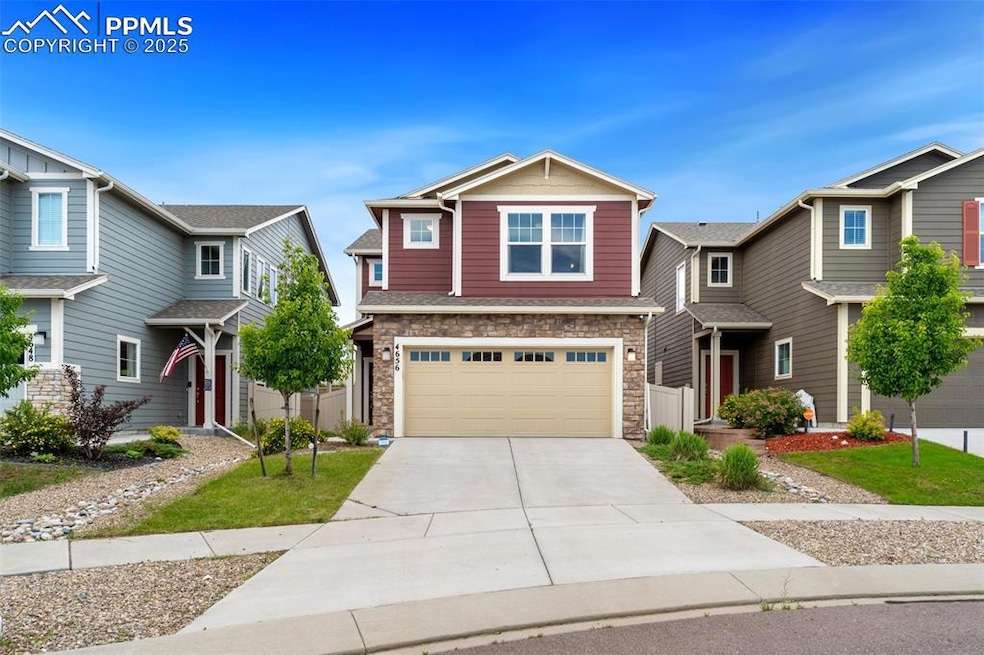 View of front of property with stone siding, driveway, and a garage