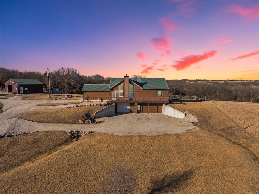 View of front of house featuring a chimney, metal roof, a garage, and dirt driveway