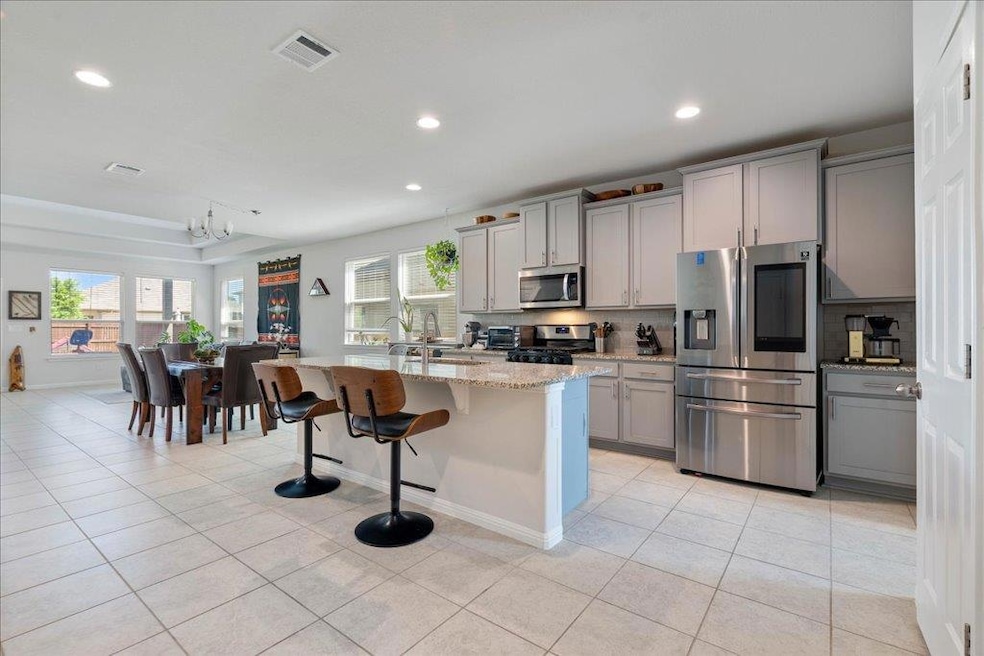 Kitchen with backsplash, gray cabinetry, light ti