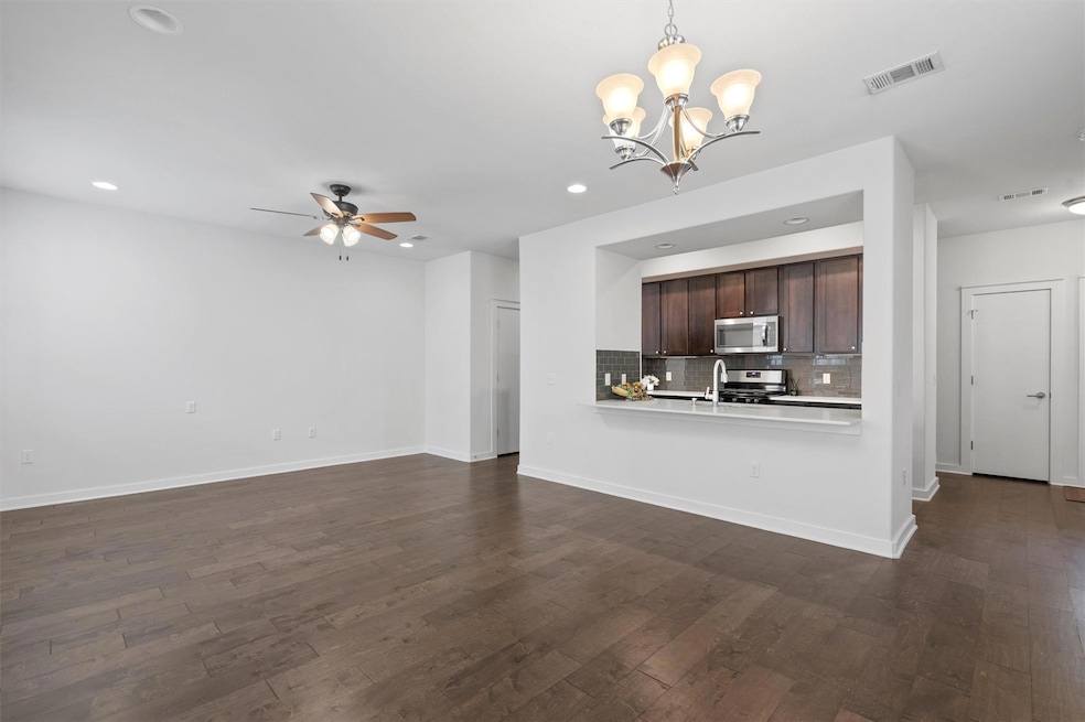 Unfurnished living room featuring a chandelier, a ceiling fan, dark wood-style flooring, recessed lighting, and baseboards