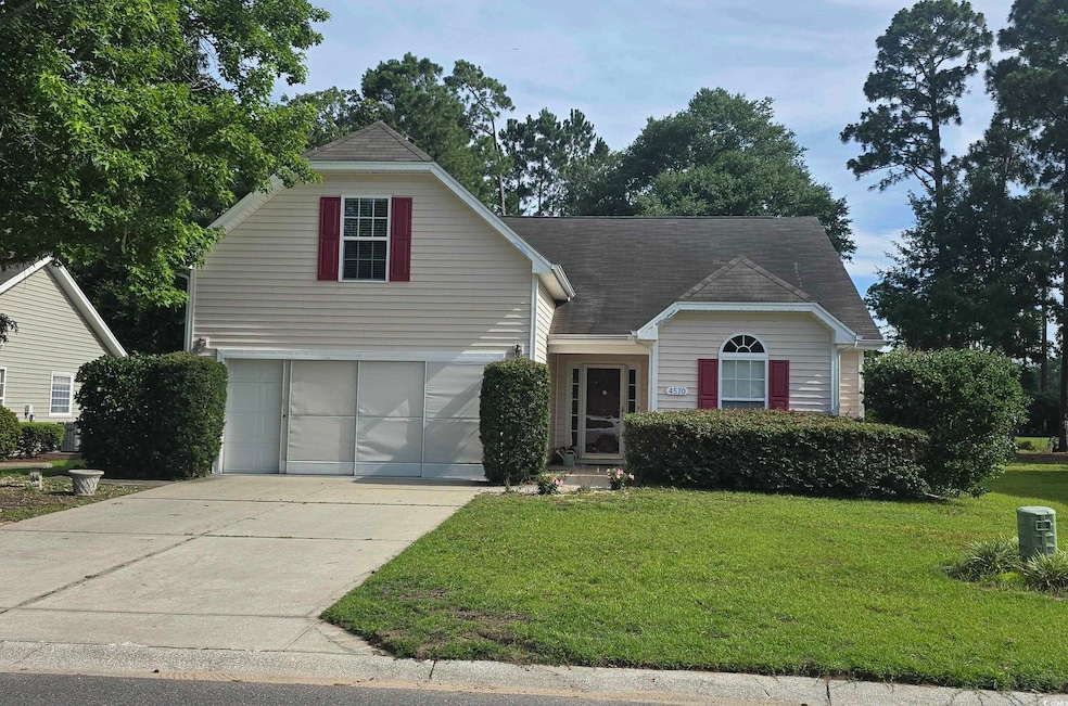 Traditional-style house with concrete driveway, a front lawn, an attached garage, and a shingled roof