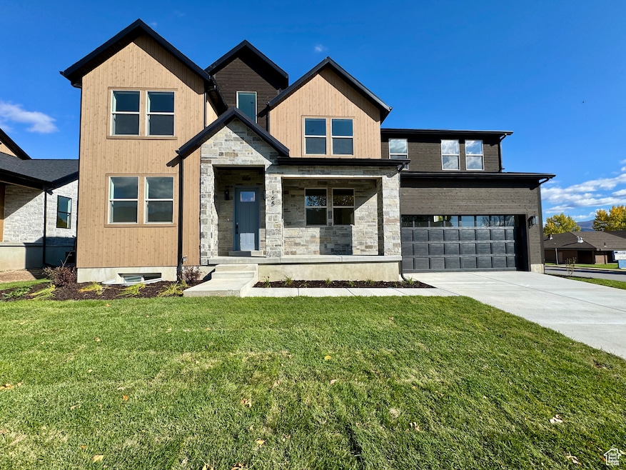 View of front of property featuring a porch, driveway, an attached garage, a front lawn, and stone siding