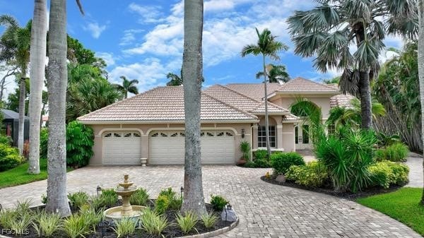 View of front of property with a tiled roof, a garage, stucco siding, and decorative driveway