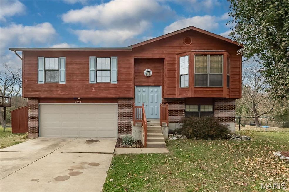 Split foyer home featuring driveway, a garage, and brick siding