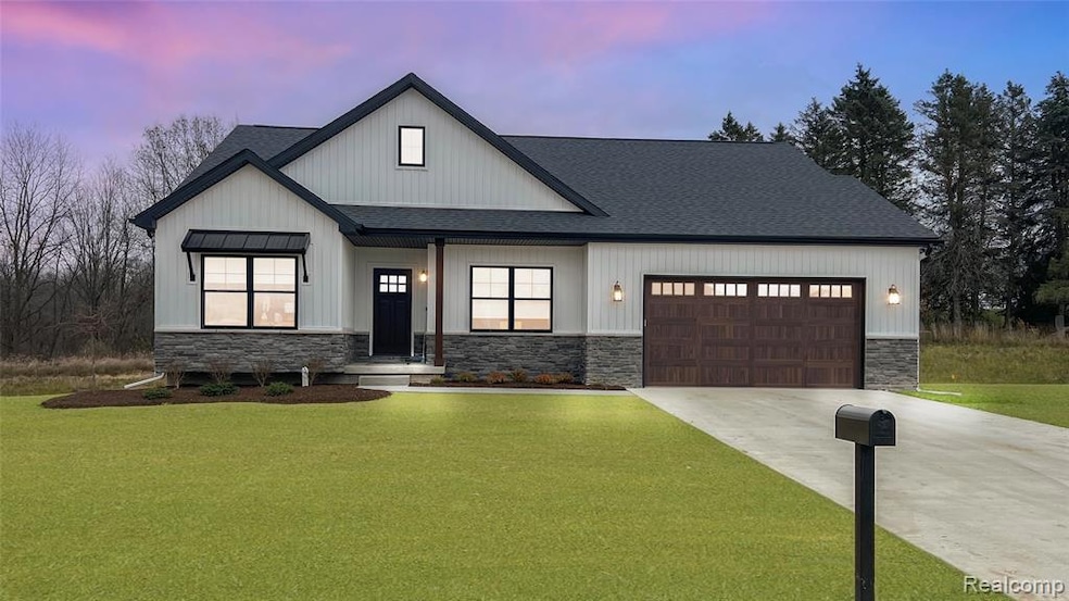 Modern farmhouse featuring stone siding, a yard, a shingled roof, driveway, and an attached garage