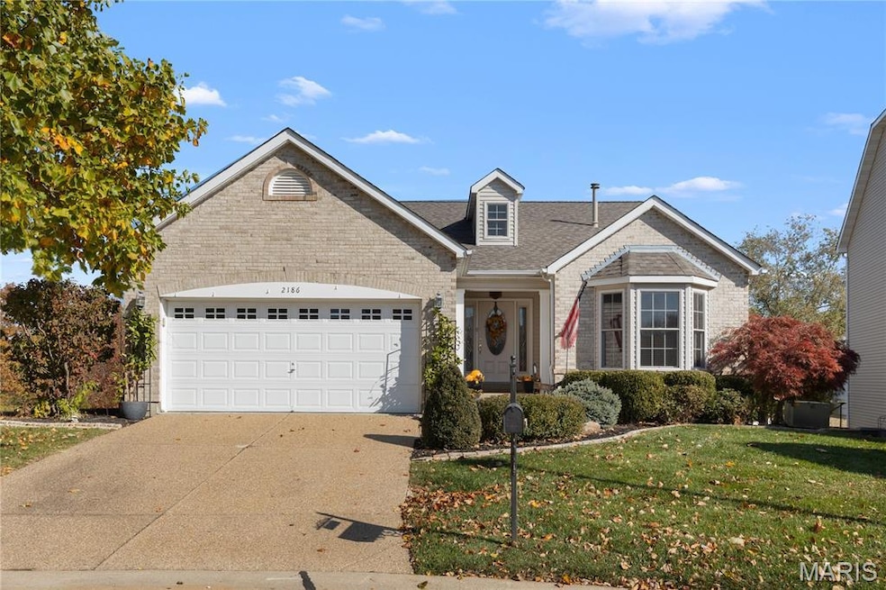 Traditional-style home featuring roof with shingles, driveway, a front yard, an attached garage, and brick siding