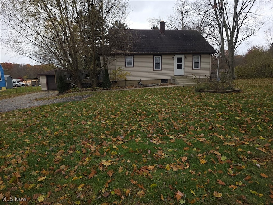 View of front of home featuring a chimney, a front yard, and an outbuilding