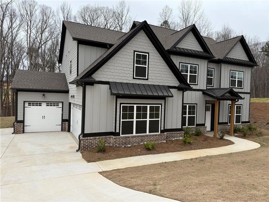 Modern farmhouse featuring board and batten siding, driveway, and a standing seam roof and 3 car garage.