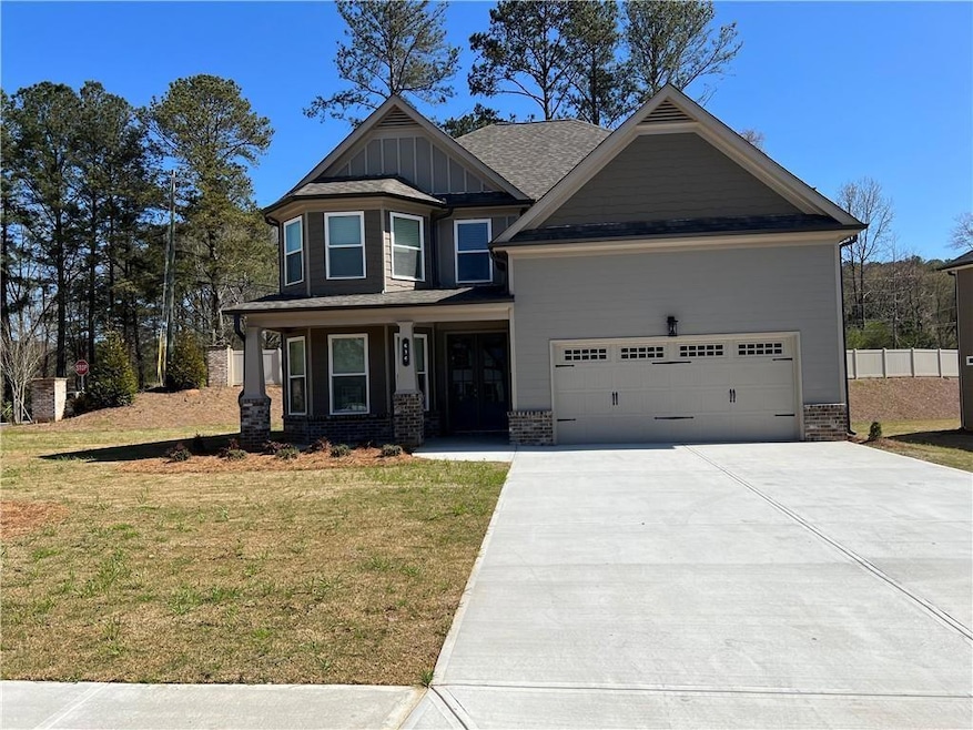 Craftsman house with concrete driveway, a front lawn, an attached garage, board and batten siding, and brick siding