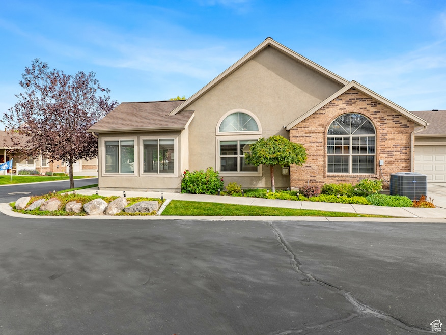 Ranch-style home with stucco siding, brick siding, an attached garage, and a shingled roof