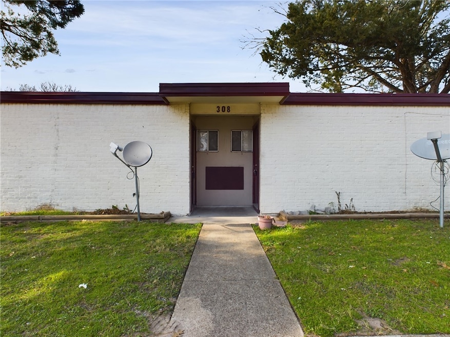 Doorway to property with a lawn and brick siding