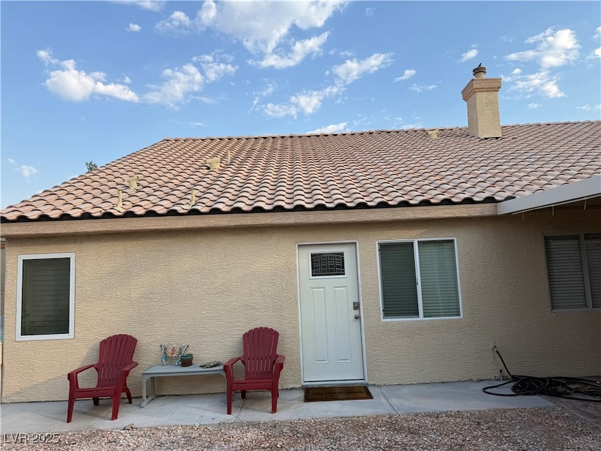 Back of property with a tile roof, a patio area, and stucco siding