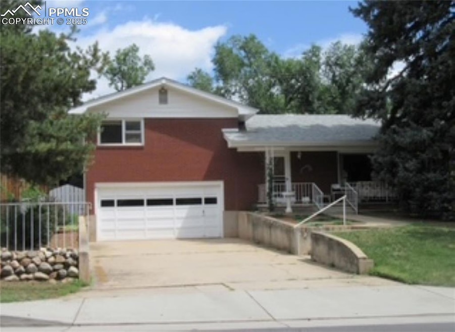 Split level home with concrete driveway, covered porch, and a garage