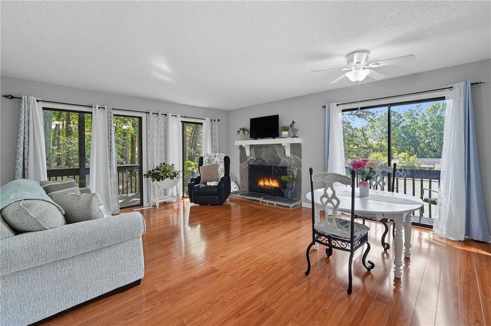 Dining space featuring a fireplace, light wood finished floors, a textured ceiling, and a ceiling fan