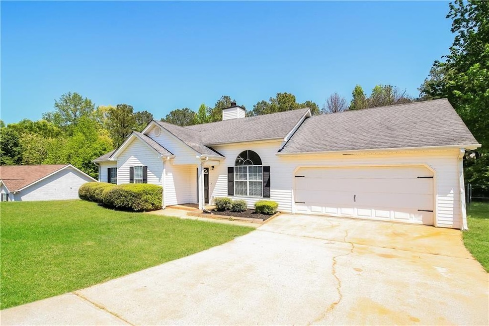 Ranch-style house featuring a chimney, concrete driveway, roof with shingles, a front yard, and a garage
