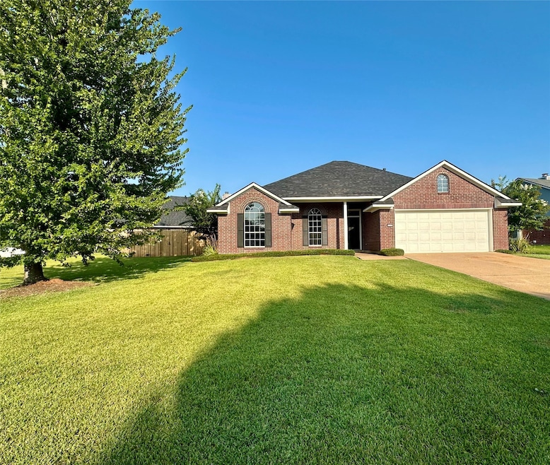 Single story home featuring concrete driveway, brick siding, an attached garage, and roof with shingles