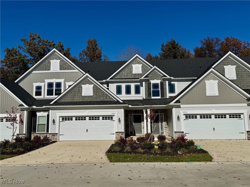 Craftsman-Townhome with covered front door, stone, vinyl siding, concrete driveway, a garage, and a shingled roof