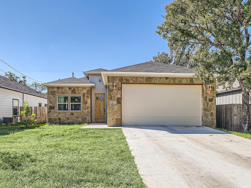View of front facade with stone siding, a garage,