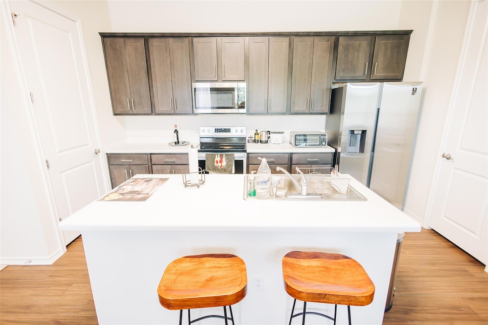 Kitchen featuring stainless steel appliances, lig