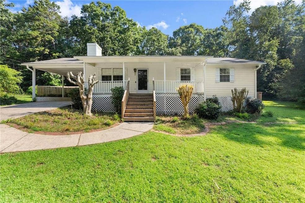 View of front of house with concrete driveway, covered porch, a front lawn, a chimney, and an attached carport