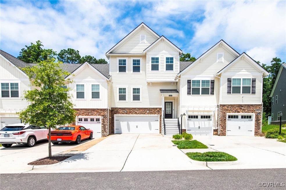 View of property featuring stone siding, driveway,