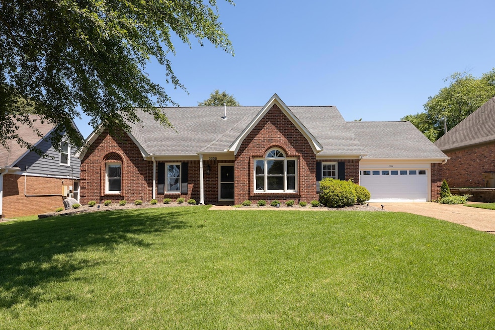 View of front of house with a shingled roof, brick siding, an attached garage, and a front lawn