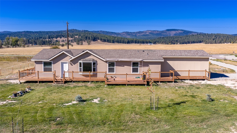 View of front of property with a shingled roof, a deck, and a front yard