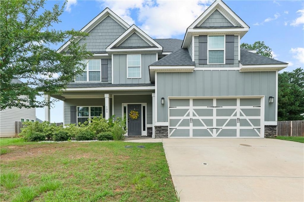 Craftsman house featuring board and batten siding, roof with shingles, and stone siding