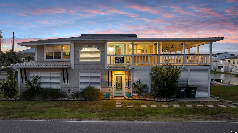 View of front of home with a balcony, a lawn, and a ceiling fan