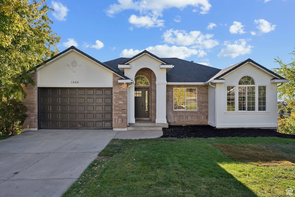Ranch-style house featuring brick siding, driveway, a garage, and a front yard