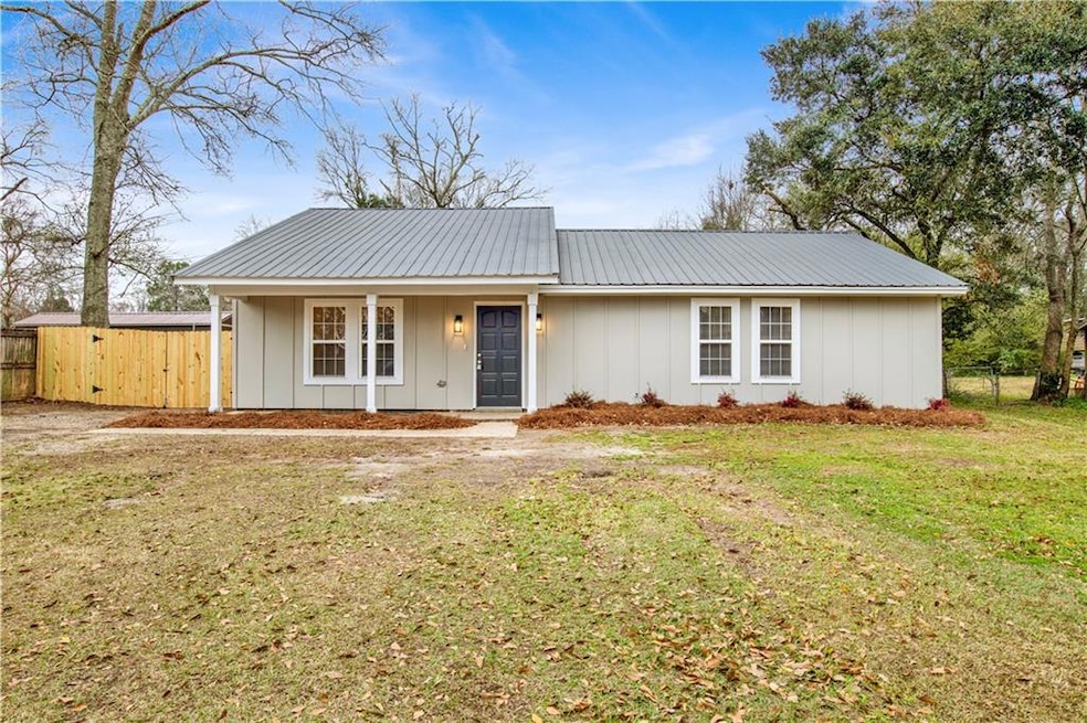 Ranch-style home featuring metal roof, a front law